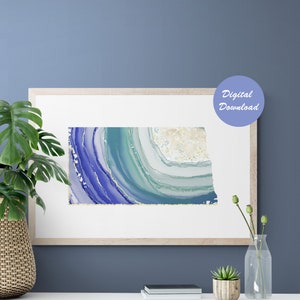 May include: A digital download of a blue and green abstract art print featuring a swirling agate design with gold accents. The print is framed and displayed on a white shelf with a plant and vase.