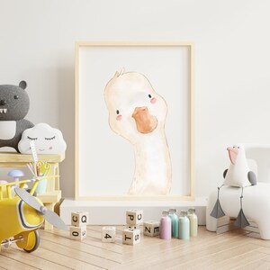 Puede incluir: Una ilustraci&oacute;n de acuarela de un lindo ganso con un pico marr&oacute;n claro y mejillas rosadas. La ilustraci&oacute;n est&aacute; enmarcada y colgada en una pared blanca en una guarder&iacute;a.