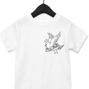 Op de afbeelding: Wit T-shirt met een zwart-witte afbeelding van een vogel met een hart en de tekst "Cry Baby".