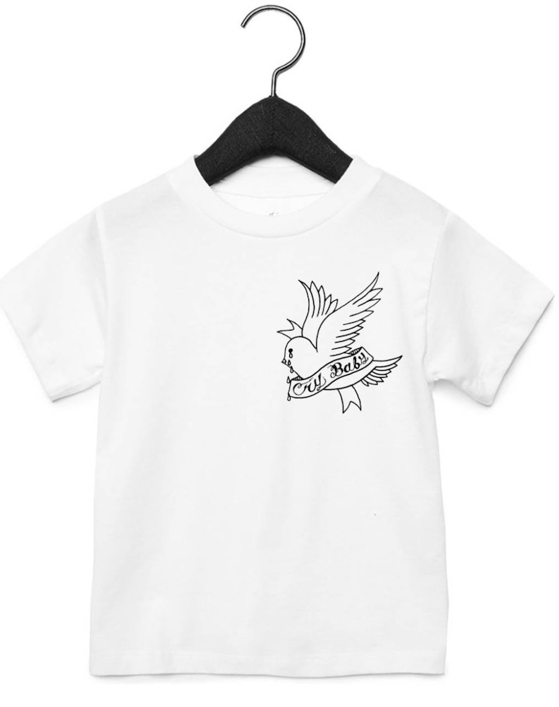 Op de afbeelding: Wit T-shirt met een zwart-witte afbeelding van een vogel met een hart en de tekst "Cry Baby".