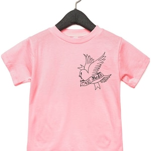 Op de afbeelding: Roze T-shirt met korte mouwen met een zwart-witte afbeelding van een vogel die een hart vasthoudt met de tekst "cry baby" erop.