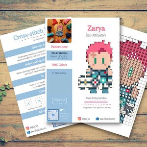 May include: Three sheets of paper with cross-stitch patterns on a wooden surface. The main sheet features a pixel art design of a character named Zarya, with a pink hairstyle. The pattern size is 18 x 27 stitches (4.6 x 6.9 cm), and 13 DMC colours are used.