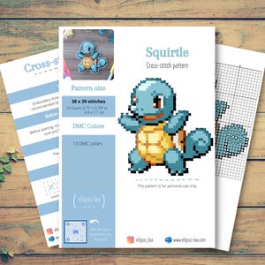 May include: A cross-stitch pattern sheet featuring a pixelated Squirtle design. The pattern includes the text "Squirtle" and details like stitch count (38 x 39 stitches) and DMC colors. The image is on a wooden surface.