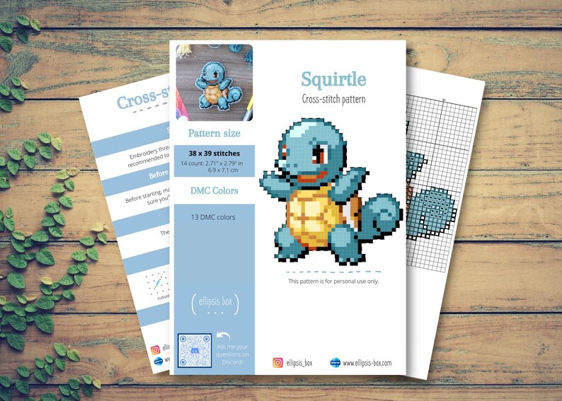 May include: A cross-stitch pattern sheet featuring a pixelated Squirtle design. The pattern includes the text "Squirtle" and details like stitch count (38 x 39 stitches) and DMC colors. The image is on a wooden surface.