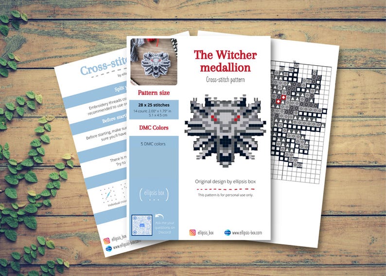 May include: Three sheets of paper with cross-stitch patterns on a wooden surface. The main sheet features a pixelated wolf medallion design with the text "The Witcher medallion". The pattern size is 2.07 x 1.79 inches.