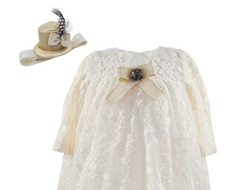 Newborn cream-colored cotton lace dress accessorized with a hat attached by sewing and a pair of matching slippers, both in gold shades.