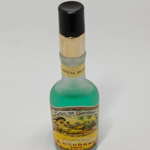 Puede incluir: Un frasco de perfume vintage con tapa negra y banda dorada. El frasco contiene l&iacute;quido verde y tiene una etiqueta con el texto "Eau de Senteur" y una ilustraci&oacute;n de mujer. El frasco est&aacute; etiquetado como "Made in France" y "R. Coudray Paris".