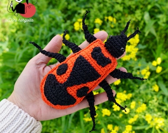 May include: A crocheted red and black ladybug with black eyes and six legs. The ladybug is held in a person's hand.