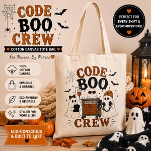May include: A beige cotton canvas tote bag featuring a graphic of three ghosts around a crash cart with the text CODE BOO CREW. The design includes a spider web, bats, and medical equipment. The bag has two shoulder straps and a flat base.