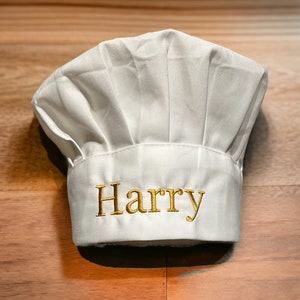 May include: White chef's hat with the name "Harry" embroidered in gold on the front.