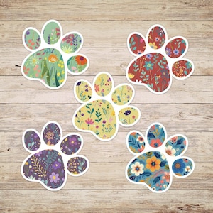 May include: Five paw print stickers with different floral patterns. The paw prints are white with a green, red, yellow, purple, and blue floral pattern.