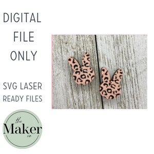 Puede incluir: Dos pendientes de madera en forma de conejo rosa con un diseño de estampado de leopardo negro. Los pendientes están sobre un fondo de madera marrón claro. El texto "DIGITAL FILE ONLY" está por encima de los pendientes. El texto "SVG LASER READY FILES" está debajo de los pendientes. El texto "the Maker co." está en un círculo debajo de los pendientes.