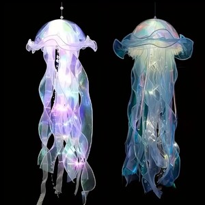 May include: Two hanging jellyfish decorations with iridescent, flowing tentacles and illuminated bodies. The jellyfish have a translucent, ruffled cap and are suspended from thin wires against a black background. The lights inside the jellyfish glow with a soft, colorful light.