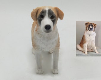 May include: A ceramic figurine of a dog sitting with its paws crossed. The dog is brown, white, and black with a white patch on its chest. The figurine is a replica of a real dog.