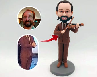 May include: A custom figurine of a person playing the violin. The figurine is wearing a brown suit and has a brown beard and glasses. The figurine is standing on a gray base.