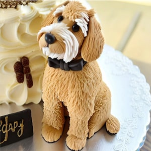 May include: A brown and white dog cake topper with a black bow tie. The dog is sitting on a white cake stand.