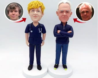 May include: Two custom-made figurines, one wearing a blue medical scrubs and the other wearing a blue sweater and jeans. Both figurines have realistic facial features and are standing on white bases.