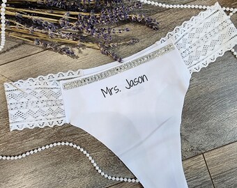 May include: White lace and satin underwear with a rhinestone trim and the text "Mrs. Jason" embroidered on the front.