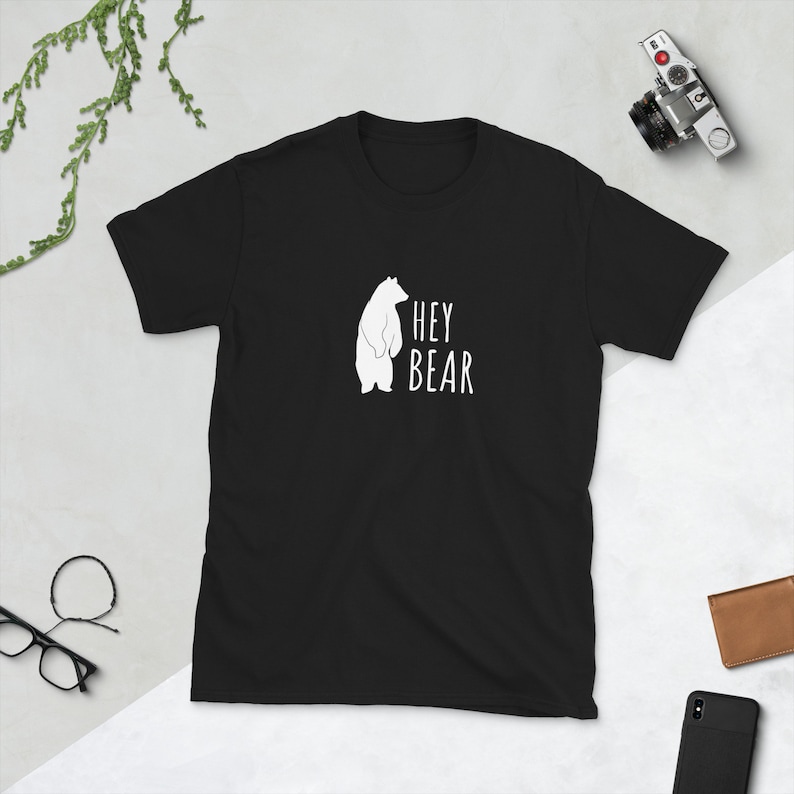 May include: Black t-shirt with a white silhouette of a bear and the text "HEY BEAR" printed on the front.