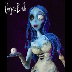May include: A figurine of the Corpse Bride character from the animated film. The figure has blue skin, blue hair, and a tattered white dress. She holds a white ball in her hand and has a surprised expression. The film's title is in white script in the upper left corner.