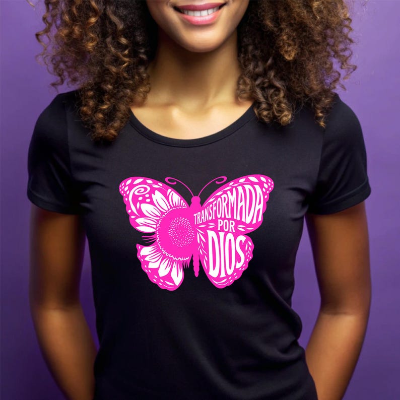May include: Black t-shirt with a pink butterfly graphic. The butterfly has the words "Transformada por Dios" written on it.