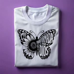 May include: White t-shirt with a black butterfly design. The butterfly is made up of the words "Transformada por Dios".