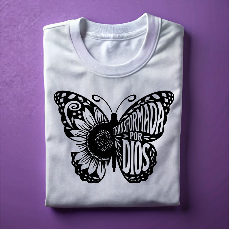 May include: White t-shirt with a black butterfly design. The butterfly is made up of the words "Transformada por Dios".