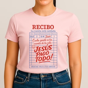 Może przedstawiać: R&oacute;żowa koszulka z grafiką paragonu, na kt&oacute;rym widnieje napis "RECIBO La cuenta est&aacute; saldada" oraz "JES&Uacute;S PAG&Oacute; TODO!" z uśmiechniętą buźką i tekstem "GRACIAS. DILE A TUS AMIGOS".