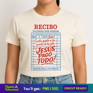 Op de afbeelding: Een wit T-shirt met een rode en blauwe afbeelding met de tekst "RECIBO La cuenta está saldada" en "JESUS PAGO TODO!" met een tabel met de tekst "Libro Capitulo Versiculo Servidor Factura" en "COLO 2 13-14 Jesus 1" en "Cada gasto a la cuenta de la vida".