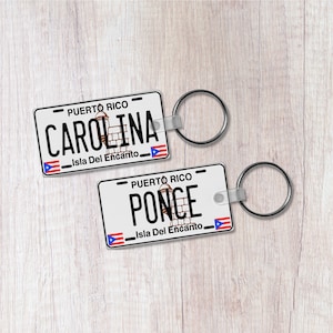 May include: Two white plastic keychains with a Puerto Rican flag design. The top keychain says "PUERTO RICO CAROLINA Isla Del Encanto" and the bottom keychain says "PUERTO RICO PONCE Isla Del Encanto".