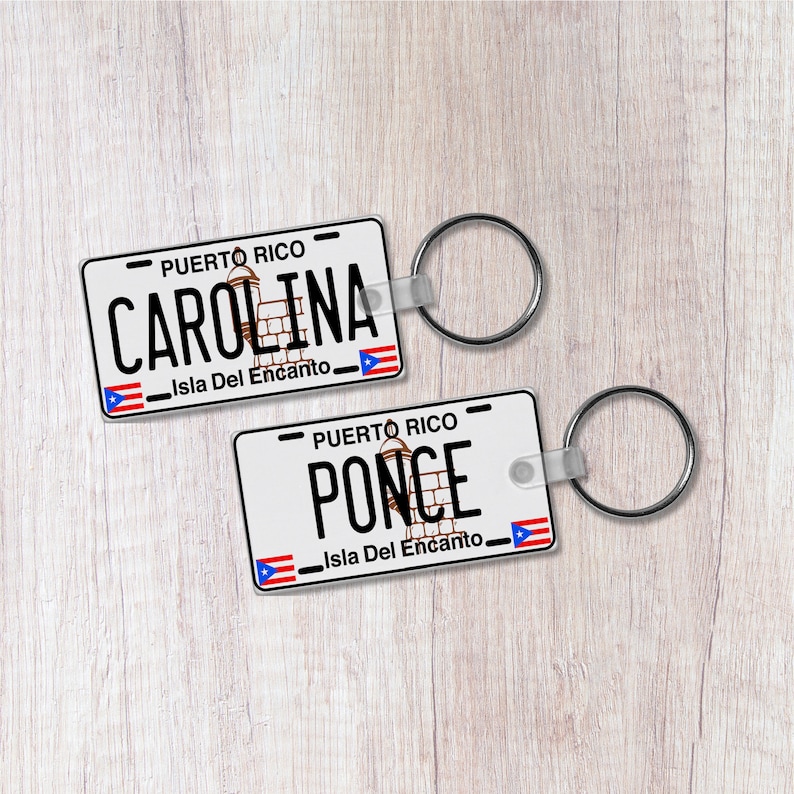 May include: Two white plastic keychains with a Puerto Rican flag design. The top keychain says "PUERTO RICO CAROLINA Isla Del Encanto" and the bottom keychain says "PUERTO RICO PONCE Isla Del Encanto".