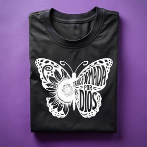 May include: Black t-shirt with a white butterfly design. The butterfly has the words "Transformada por Dios" written on its wings.