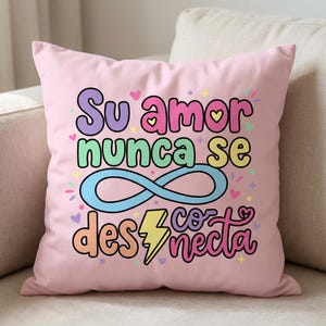 May include: A pink decorative pillow with the Spanish text "Su amor nunca se desconecta" in colorful bubble letters. The design includes hearts, stars, an infinity symbol, and a lightning bolt.