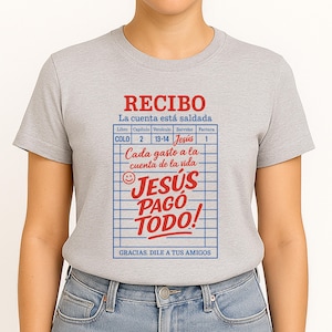 Może przedstawiać: Szary T-shirt z czerwono-białym wzorem paragonu, na kt&oacute;rym widnieje napis "RECIBO" i "La cuenta est&aacute; saldada". Paragon zawiera r&oacute;wnież napis "JES&Uacute;S PAGO TODO!" i "GRACIAS. DILE A TUS AMIGOS".