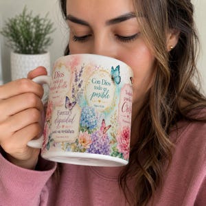 May include: White ceramic mug with floral and butterfly designs, featuring the text "Con Dios todo es posible" and other Spanish text. The mug has a curved handle and is filled with a beverage.