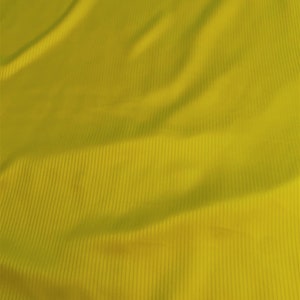 May include: A close-up of a yellow fabric with a ribbed texture. The fabric is wrinkled and has a soft, smooth feel.