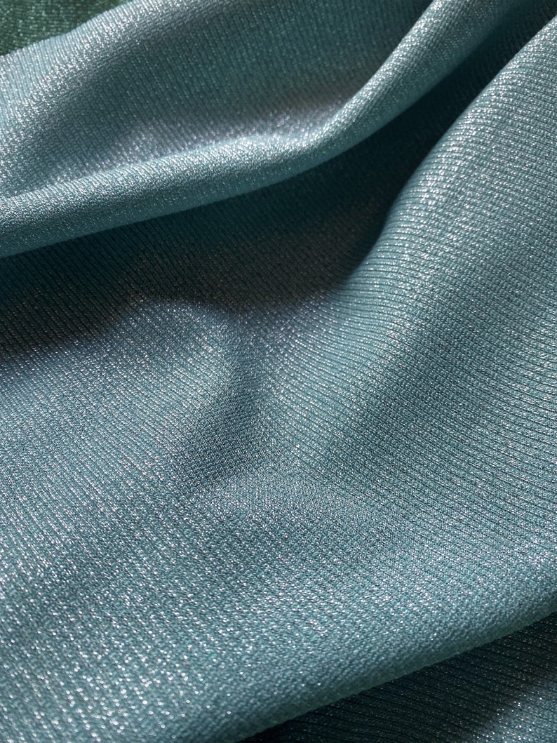 May include: Close-up of a soft, blue fabric with a subtle shimmer. The fabric has a textured, ribbed surface.