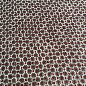 Peut inclure: Gros plan sur un tissu avec un motif g&eacute;om&eacute;trique blanc et rouge. Le tissu a une surface textur&eacute;e et un motif r&eacute;p&eacute;titif de petits cercles.