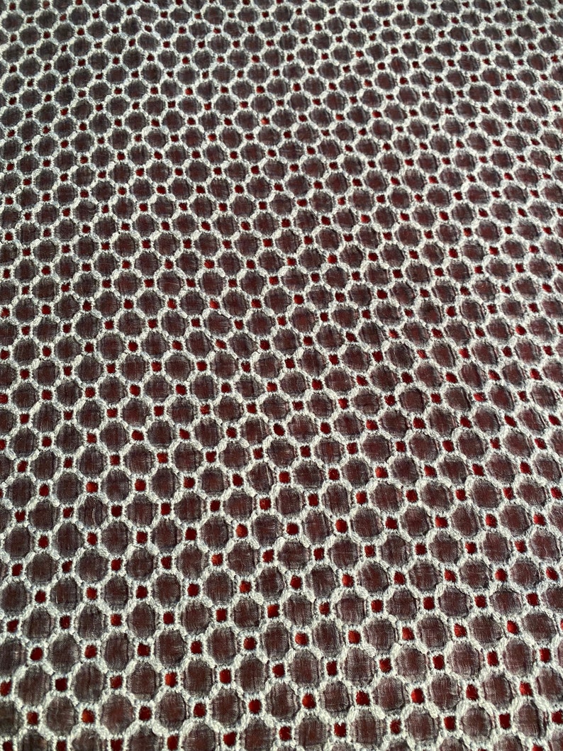 Peut inclure: Gros plan sur un tissu avec un motif g&eacute;om&eacute;trique blanc et rouge. Le tissu a une surface textur&eacute;e et un motif r&eacute;p&eacute;titif de petits cercles.