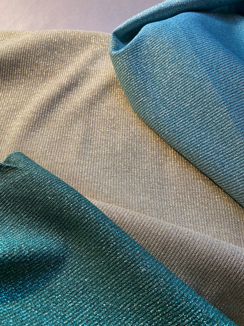 May include: Three fabric swatches in different colors: teal, silver, and light blue. The fabric has a shimmery, sparkly texture.