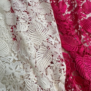Puede incluir: Dos piezas de tela de encaje blanca y rosa con un patrón floral. El encaje es delicado e intrincado.