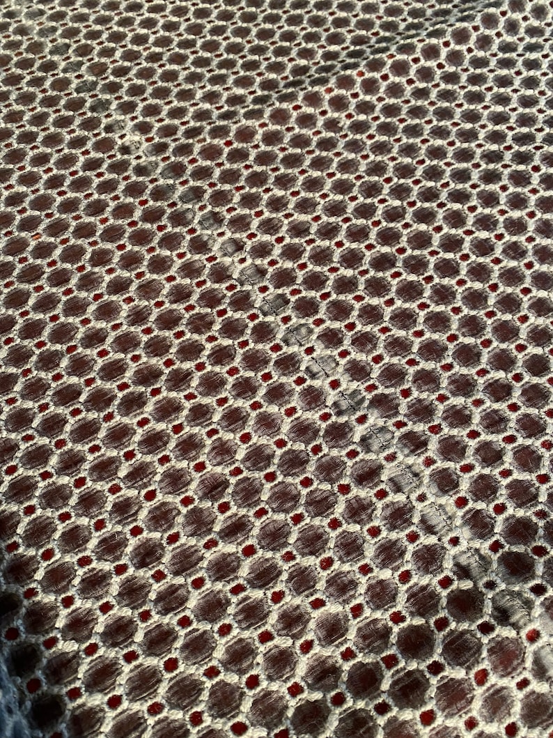 Peut inclure: Gros plan sur un tissu avec un motif g&eacute;om&eacute;trique r&eacute;p&eacute;titif. Le motif est compos&eacute; de petits cercles blancs et de points rouges, dispos&eacute;s en grille. Le tissu a une surface textur&eacute;e.