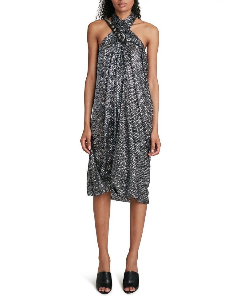 May include: A silver sequined halter dress with a knotted detail at the neckline. The dress has a loose, flowing fit and is midi length.