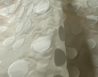 May include: White fabric with a polka dot pattern. The dots are raised and have a white outline.