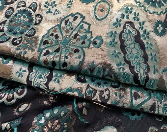 May include: Teal and silver brocade fabric with a floral pattern. The fabric has a metallic sheen and is ideal for upholstery or clothing.