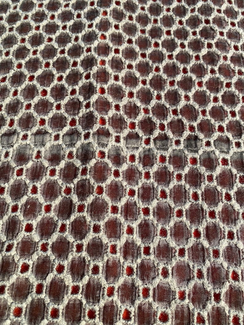 Peut inclure: Gros plan sur un tissu avec un motif r&eacute;p&eacute;titif de cercles blancs et de points rouges sur un fond brun fonc&eacute;.