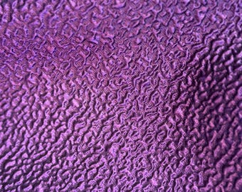 May include: Close-up of a textured purple fabric with a subtle sheen. The fabric has a raised, bumpy surface that creates a unique visual effect.