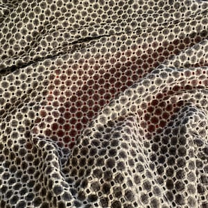 Peut inclure: Un tissu noir et blanc avec un motif g&eacute;om&eacute;trique de petits cercles et carr&eacute;s. Le tissu est textur&eacute; et a un aspect l&eacute;g&egrave;rement froiss&eacute;.