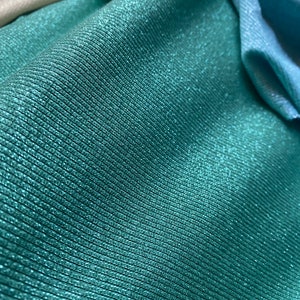 May include: Teal fabric with a subtle shimmer and a ribbed texture.