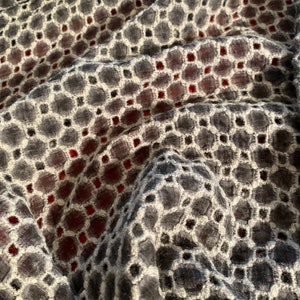 Peut inclure: Gros plan sur un tissu noir et blanc avec un motif g&eacute;om&eacute;trique. Le tissu a une texture en relief et une subtile teinte rouge.
